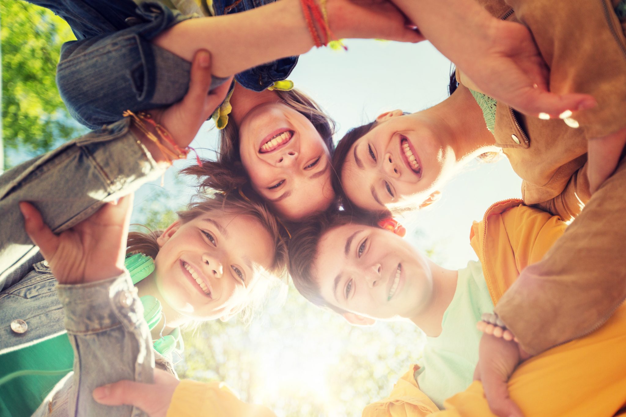 friendship and people concept - group of happy teenage friends holding hands outdoors